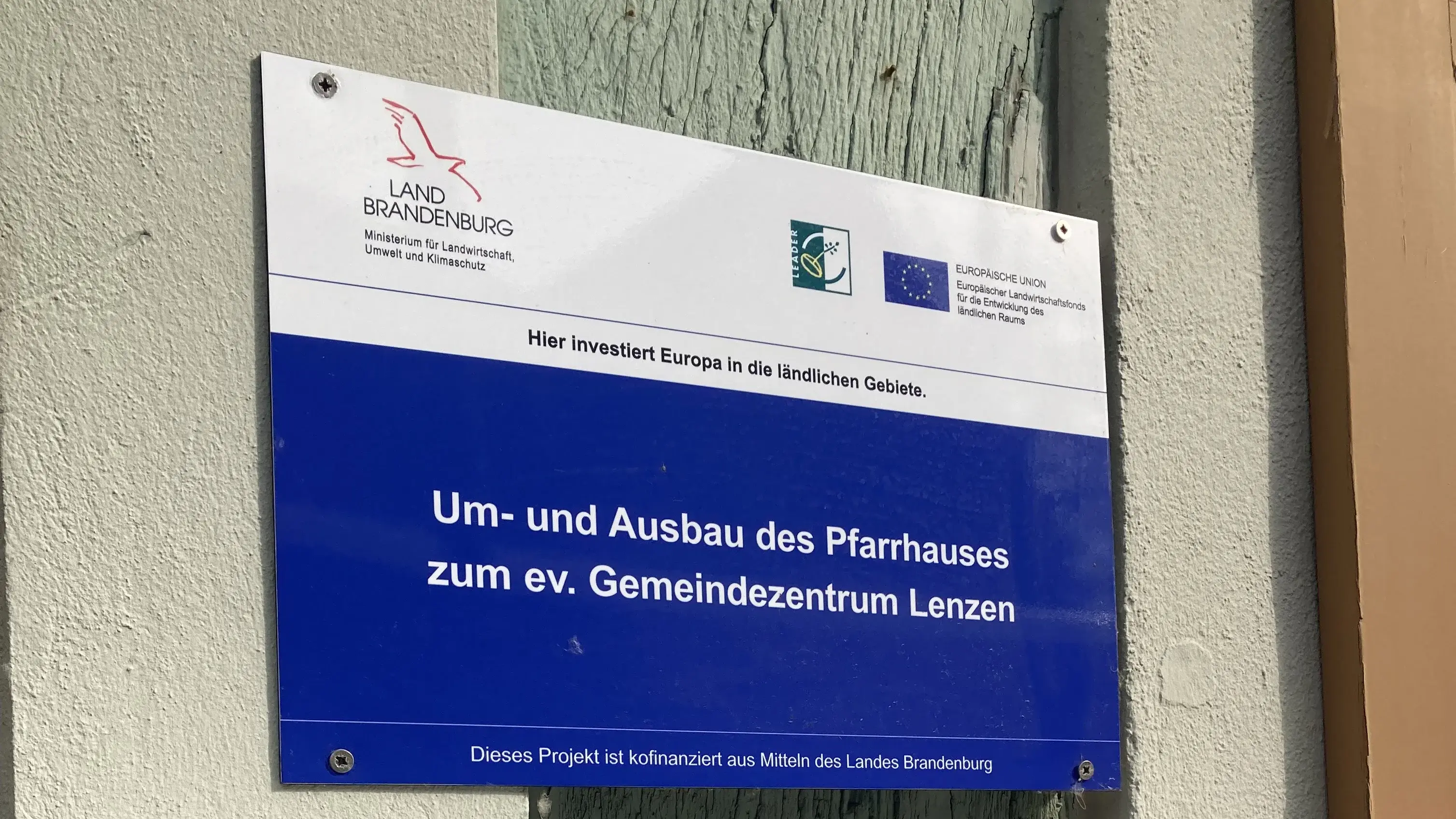 Auf dem Bild sieht man eine Plakette. Sie weißt darauf hin, dass der Umbau des Gemeindehauses in Lenzen mit Geldern aus der Europäischen union unterstützt wurde.