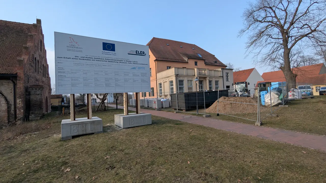 Auf dem Bild sieht man ein großes Baustellenschild, dass auf die Sanierung und dem Umbau des Amtshauses in Lehnin hinweist. AUßerdem auf die Fördergelder, die für dieses Projekt bereitgestelltu wurden. 