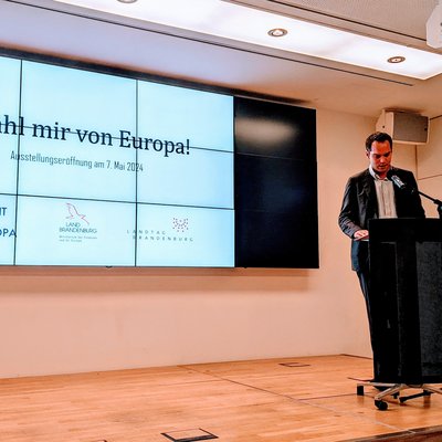 Auf dem Foto sieht man einen Redner am Pult zur Austellungseröffnung "Erzähl mir von Europa" im Brandenburger Landtag.