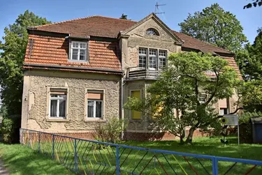 Das Foto zeigt das denkmalgeschützte Pfarrhaus in Radensleben. Die Sanierungsnotwendigkeit ist durch abgeplatzten Putz erkennbar.