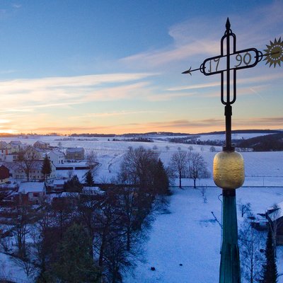 Turmkreuz im Sonnenaufgang im Winter